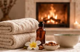 Spa towels and oil beside a fireplace