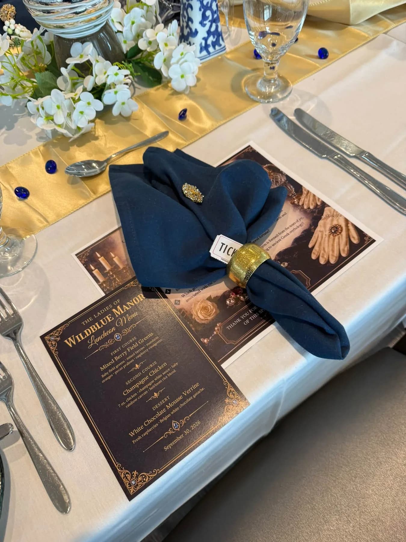 A navy napkin and gold napkin ring beside the luncheon menu