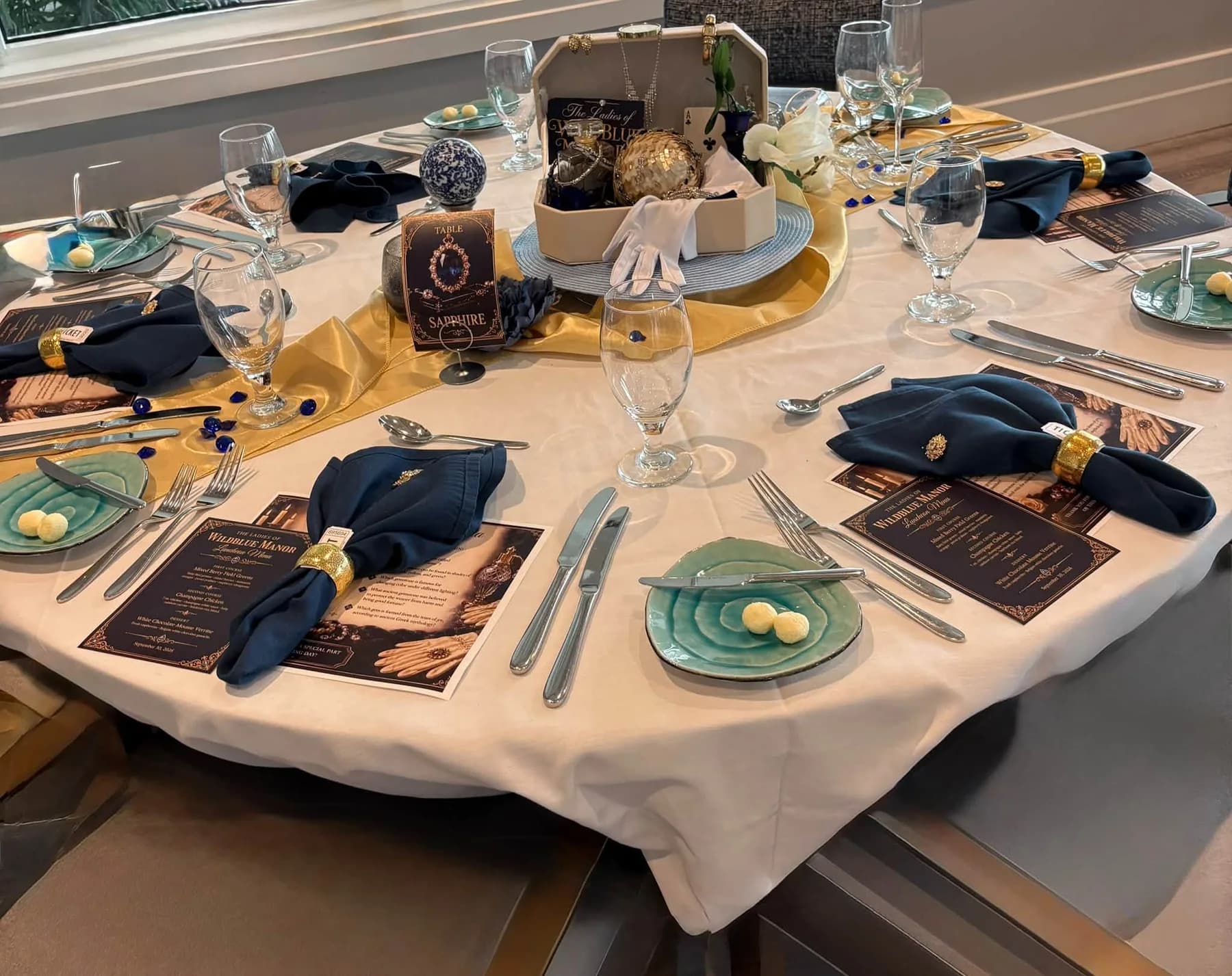 A round luncheon table set with navy napkins, gold accents, and blue plates
