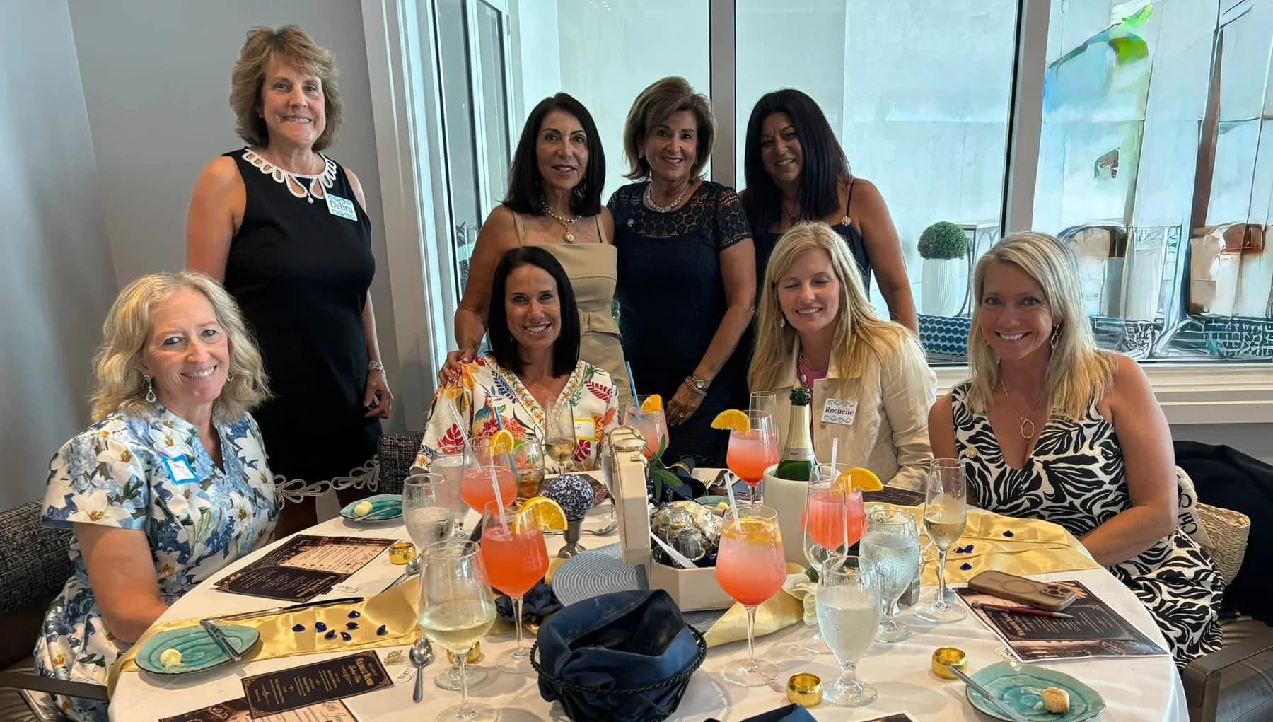 A group of friends seated and standing together at the luncheon