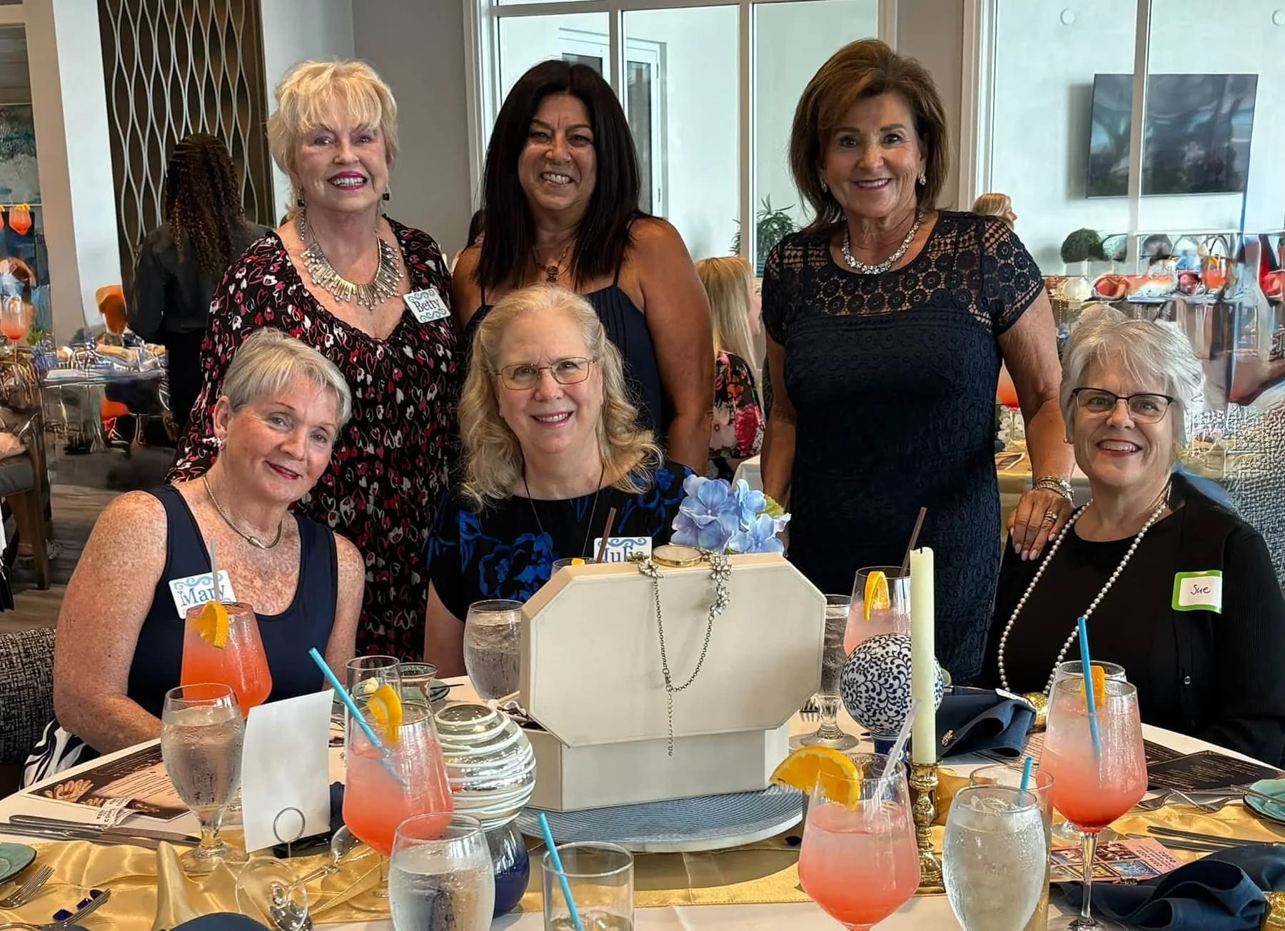 Guests gathered behind a jewelry-box centerpiece and colorful drinks