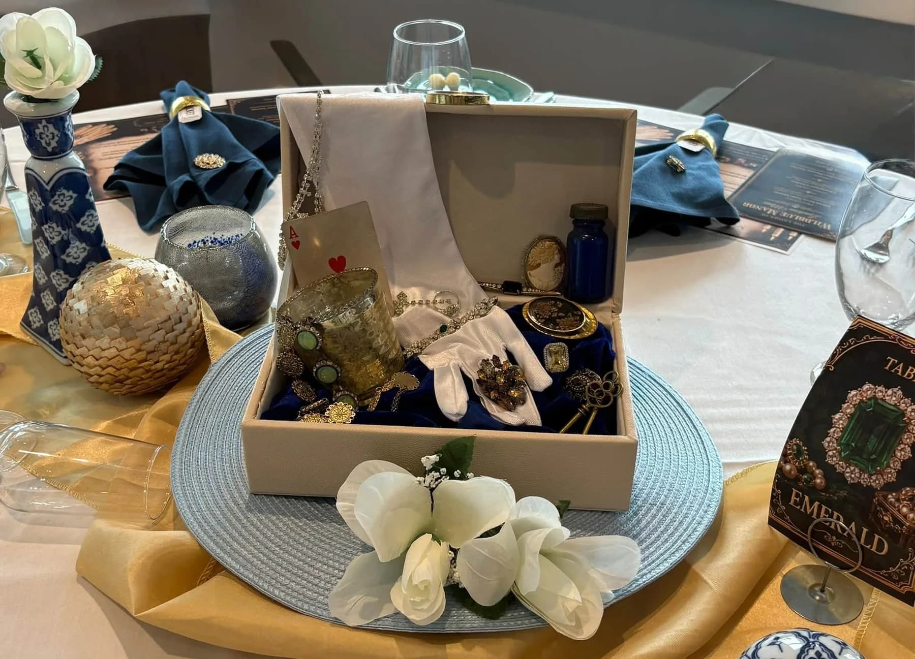 An open jewelry box with flowers and sparkling decorations on a gold runner