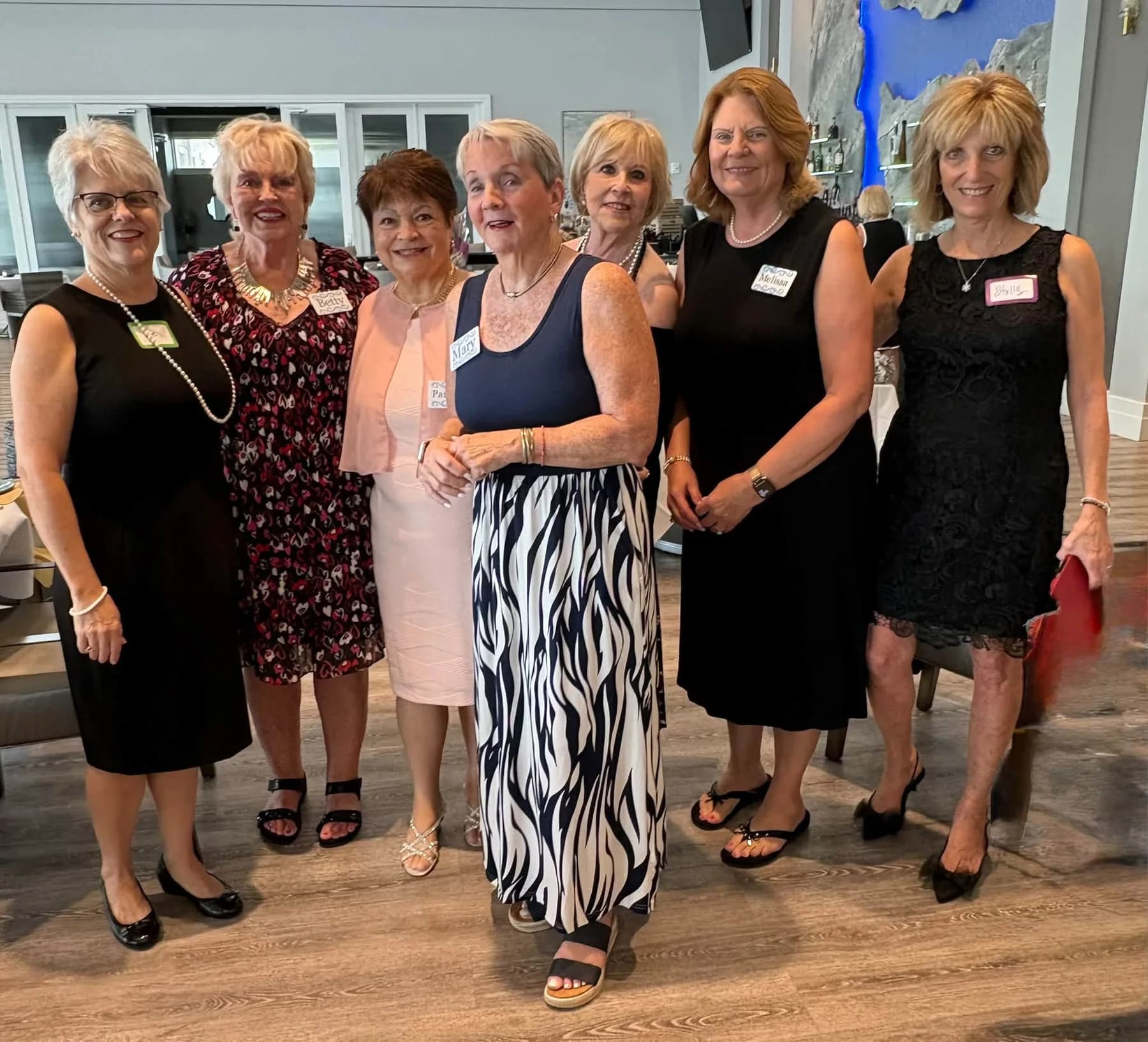 Seven friends posing together in the luncheon dining room