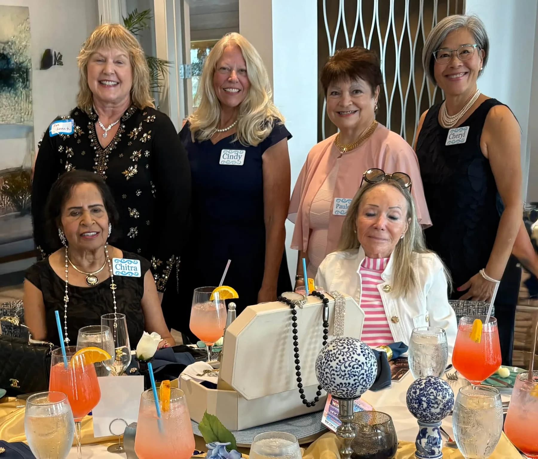 Six luncheon guests gathered around a table for a photo