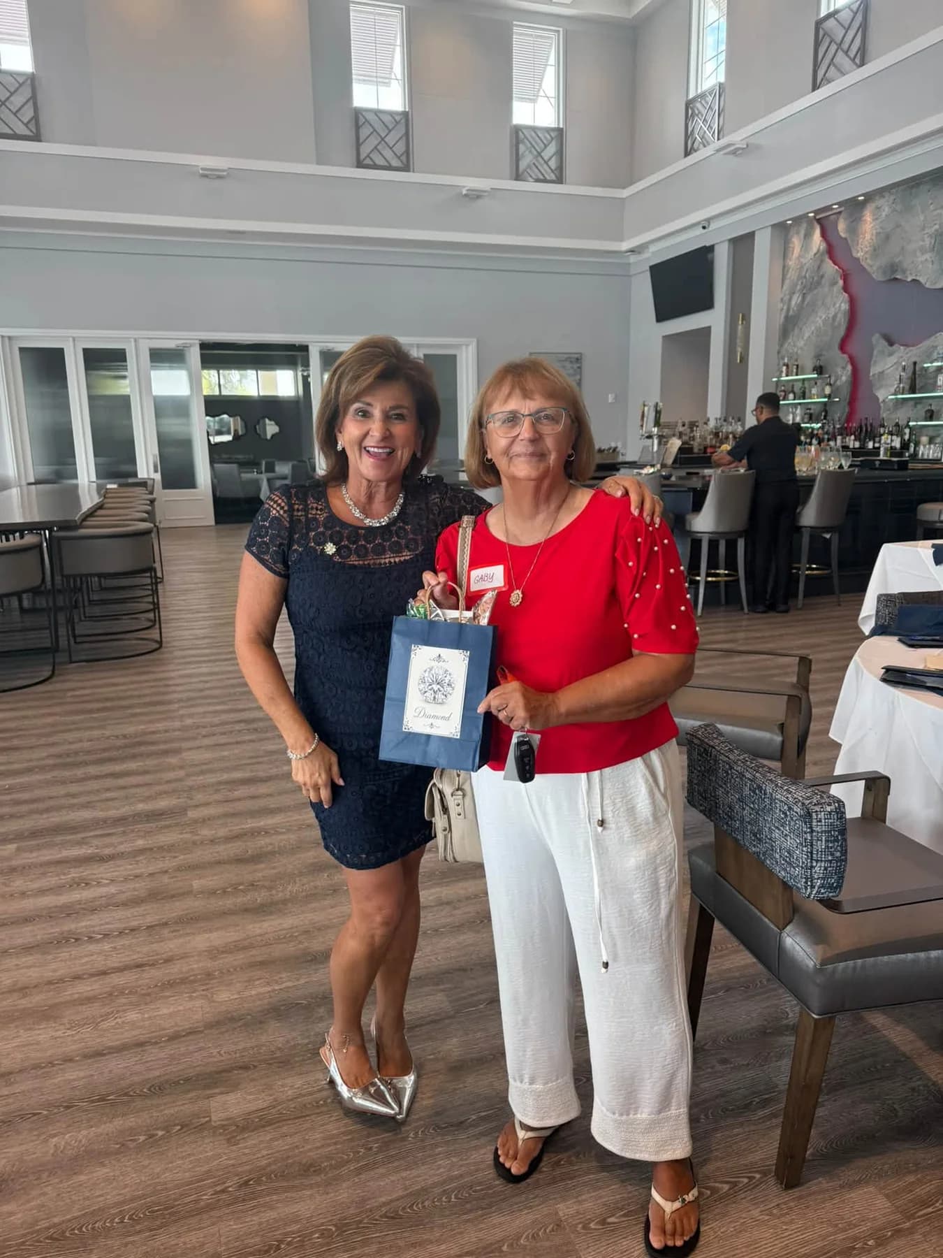 Two friends holding a gift bag in the dining room